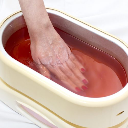 Process paraffin treatment of female hands in beauty salon